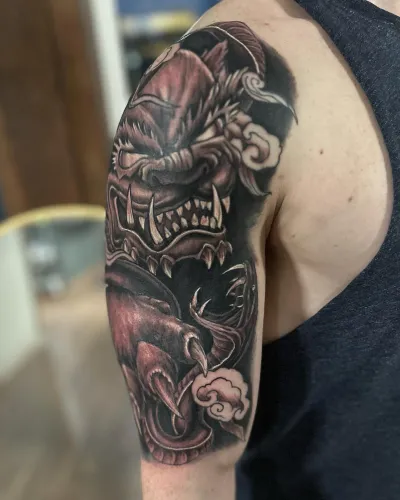 Black and grey dragon and skull half sleeve on an upper arm — by Adam Crane at Ministry Ink