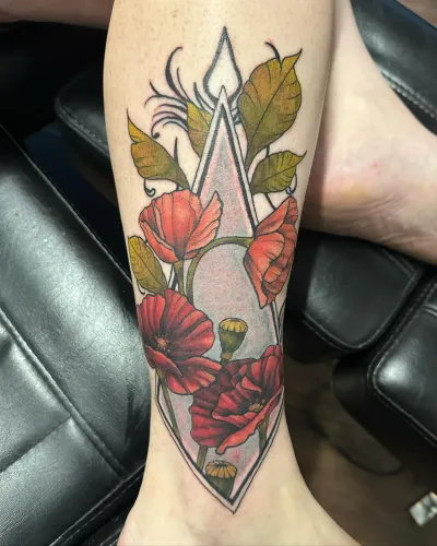 Neo-traditional poppies and foliage inside a geometric diamond on an arm — by Adam Crane at Ministry Ink