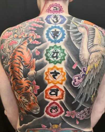 Full colour back piece with chakra symbols, a tiger, a crane and cherry blossom — by Adam Crane at Ministry Ink