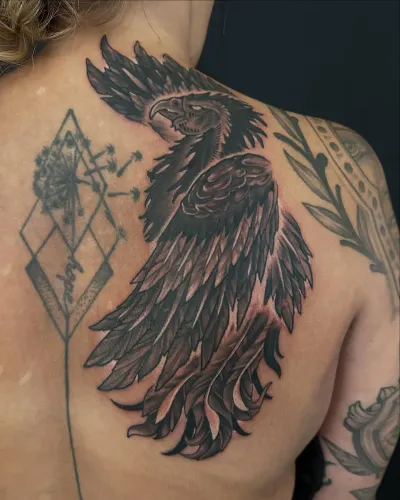 Black and grey raven with fine geometric linework across a shoulder blade — by Adam Crane at Ministry Ink