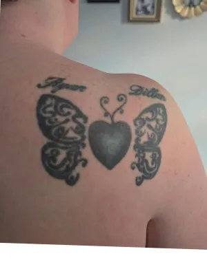 Fine line butterflies either side of a heart locket with script names, upper back — by Adam Crane