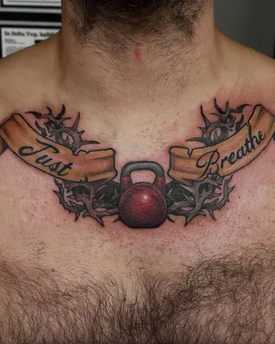 Kettlebell flanked by Just Breathe banner ribbons across the chest — by Adam Crane at Ministry Ink