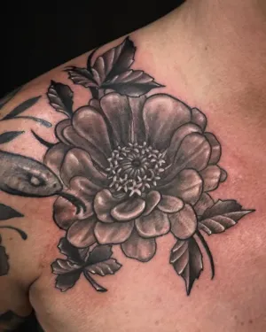 Black and grey peony and foliage tattooed on a chest — by Adam Crane