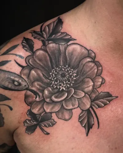 Black and grey peony and foliage tattooed on a chest — by Adam Crane at Ministry Ink