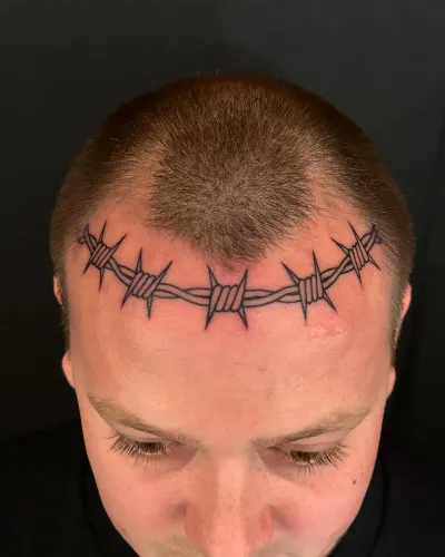 Barbed wire tattooed across a shaved scalp hairline — by Chay Menke at Ministry Ink