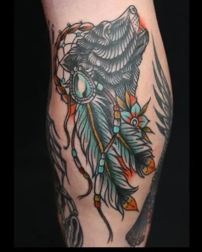 American traditional wolf head with feathers and beadwork on a calf — by Chay Menke at Ministry Ink