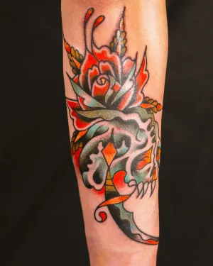 American traditional roses and foliage in orange and green on a forearm — by Chay Menke