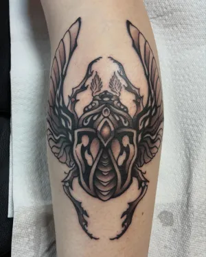 Black and grey winged ornamental piece on a forearm — by Chay Menke
