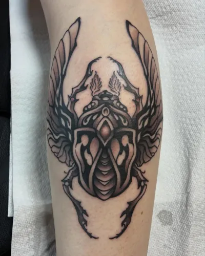Black and grey winged ornamental piece on a forearm — by Chay Menke at Ministry Ink