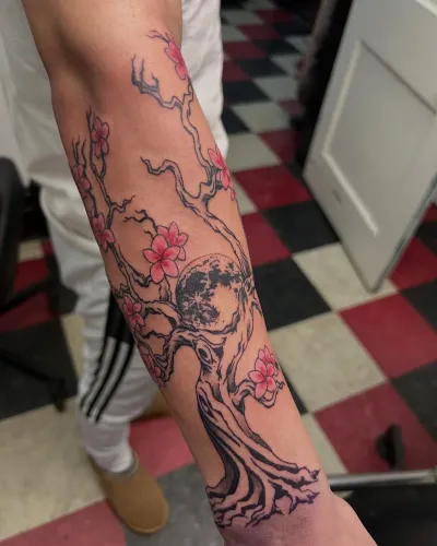 Fine line cherry blossom branch running down a forearm — by Gabriel Gonzalez at Ministry Ink